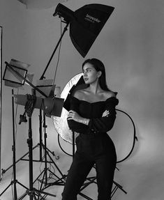 a black and white photo of a woman posing in front of photography equipment