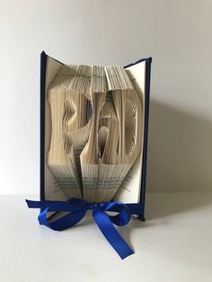 an open book with blue ribbon on the front and side, showing two folded pages