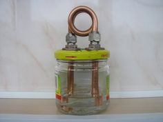 a glass jar with two metal handles on top of a shelf next to a wall