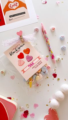 a candy bag with hearts on it next to some confetti and a card