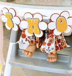 a baby sitting in a highchair with flowers on it's back legs