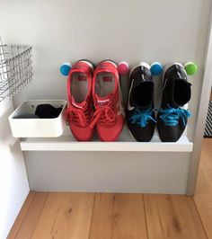 three pairs of shoes are lined up on a shelf in front of a wall mounted shoe rack