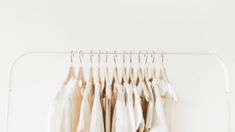 clothes hanging on a rack in front of a white wall