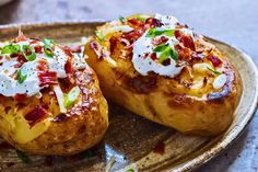 two baked potatoes on a plate topped with sour cream