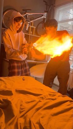 two people standing in a room with fire coming out of their hands