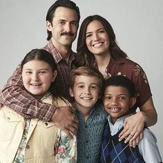 a group of people standing next to each other in front of a white background with one person holding the child