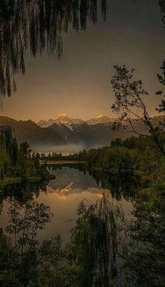 a lake surrounded by trees with mountains in the background