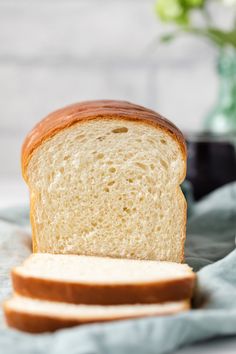 a loaf of white bread sitting on top of a blue cloth next to a slice of bread