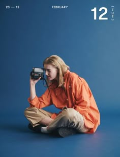 a woman sitting on the ground holding a camera