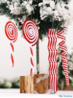 some candy canes are hanging from a christmas tree with snow on the ground behind them