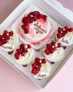 a white box filled with cupcakes covered in frosting and raspberries