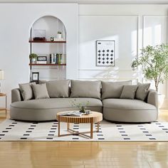 a living room filled with furniture on top of a hard wood floor covered in white rugs