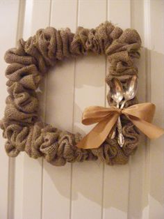 a burlap wreath with a bow hanging on the front door and a spoon in it