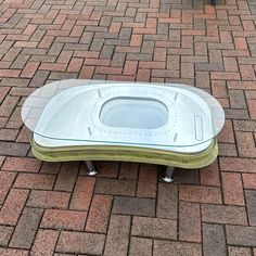 a glass and metal bench sitting on top of a brick sidewalk