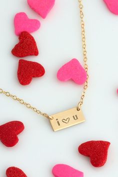 red and pink hearts scattered around a gold plated necklace with the word u on it