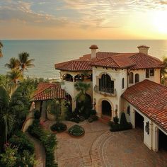 an aerial view of a mansion with the ocean in the background at sunset or sunrise