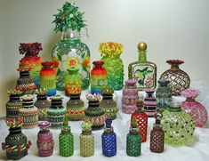 there are many colorful vases and jars on the white tablecloth, all lined up together