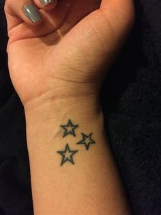 a woman's wrist with three stars tattooed on the left side of her arm