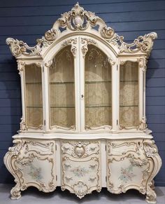 an antique china cabinet with glass doors and ornate carvings on the front, painted in white