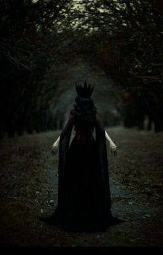 a woman wearing a crown and cloak standing in the woods