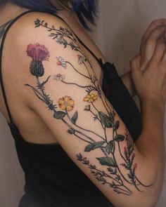 a woman's arm with flowers and leaves on it