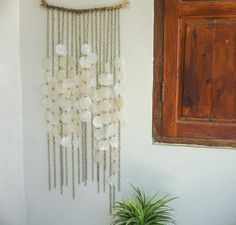 a potted plant sitting next to a wall hanging with beads and shells on it