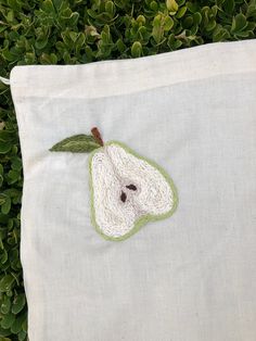 an embroidered apple sitting on top of a white pillow