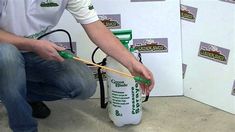 a man kneeling down next to a green and white container with a stick in it