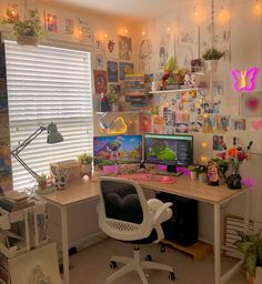 a desk with two computers on it in front of a window filled with pictures and plants