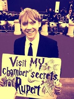 a young man in a suit and tie holding a sign