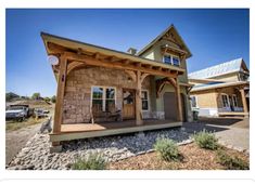 a small house with a covered porch in the middle of a yard and lots of rocks