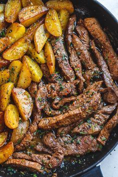 steak and potatoes in a skillet on a white table with a napkin next to it