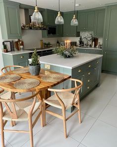 an image of a kitchen setting with green cabinets and white tile flooring in it