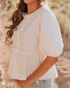 Make your summer outfits pop with THE AMBER TIE FRONT TOP! This trendy white top features a playful tie front and puff sleeves for a cute and stylish look. Perfect for any summer occasion, it's a must-have in your wardrobe. Puff sleeves Relaxed fit Tie bow front Round neck 100% cotton Paired with THE LILO HIGH RISE DISTRESSED BERMUDA SHORTS IN MEDIUM WASH Runs true to size. Small (0-4), Medium (4-8), Large (8-12).Model is 5'1" wearing a small.To view our return policy, click here! Check out our Happy Threads, Summer Goddess, Distressed Bermuda Shorts, Pink Desert, Tie Front Top, Exclusive Clothing, Tie Bow, Front Tie Top, British Indian