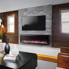 a living room with a large television mounted on the wall and a fire place in front of it