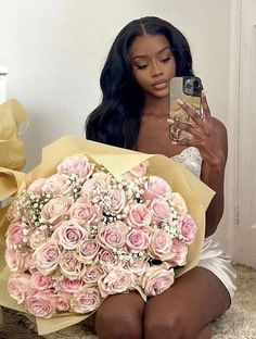 a woman sitting on the floor holding a bouquet of roses and a cell phone in her hand