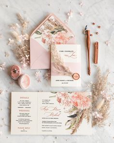 the wedding stationery is laid out on top of pink and white flowers, along with other items