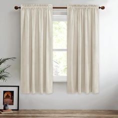 a white curtain hanging on the side of a window next to a potted plant