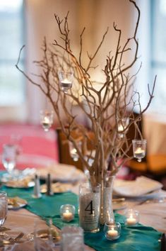 an image of a table setting with candles and branches in vases on the table