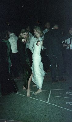 two women in white dresses are dancing at a party