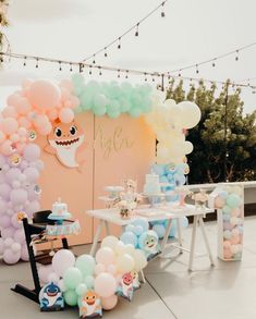 an outdoor party with balloons, cake and other decorations on the table in pastel colors