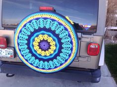 a blue and yellow crochet doily is on the back of a jeep