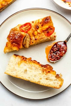 two slices of pizza sitting on top of a white plate next to an orange sauce