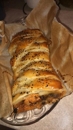 a loaf of bread sitting on top of a glass plate covered in cheese and black pepper