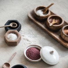 various bowls and spoons with different types of spices in them on a white surface