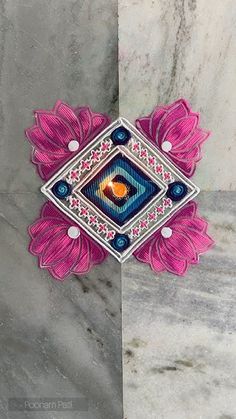 a pink and blue brooch sitting on top of a marble counter next to a white wall