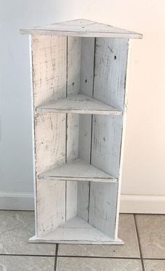 a white shelf with three shelves on top of it in front of a tiled floor