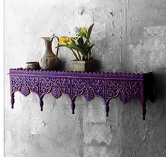 a purple shelf with vases and flowers on it