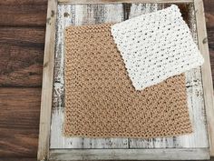 two crocheted squares sitting on top of a wooden table next to each other