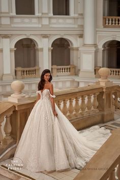 a woman in a white wedding dress standing on stairs with her hand on her hip